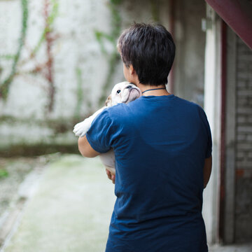 Rear sight of woman hugging bulldog puppy