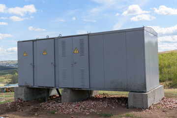 Mobile power distribution substation in Russia. A warning notice on the doors. Metal body. Green forest, clouds. The concept of power supply for remote industrial and residential.