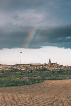 Conceptual picture of an electric windmills on a windy day with rainbow at background.