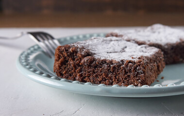 Postre brownie achocolatado glaseado en plato azul con tenedor