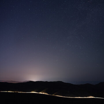 Night sky and illuminated mountain road