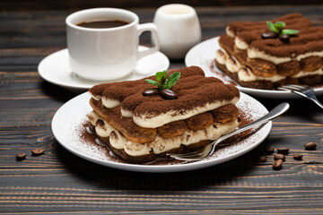 Two portions of Classic tiramisu dessert, cup of coffee and milk or cream on wooden background