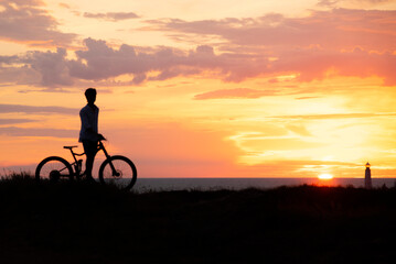 Fototapeta na wymiar Silhouette of a young man with a Bicycle against the background of a sunset.