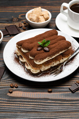 portion of Classic tiramisu dessert, cup of coffee and milk or cream on wooden background