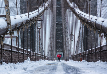 Tourist standing on Brooklyn Bridge in snow, New York