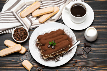 portion of Classic tiramisu dessert, cup of coffee and milk or cream on wooden background