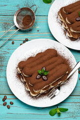 Two portions of Classic tiramisu dessert on ceramic plate on colorful blue wooden background