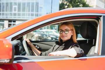 successful businesswoman driving car through modern urban city with reflections of buildings