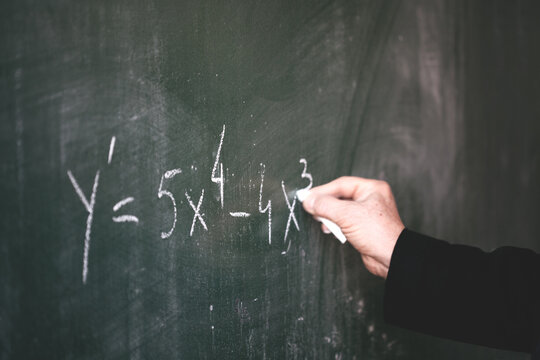 professor writing on a blue blackboard with chalk