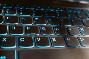 Close up shot of blue backlit laptop keyboard