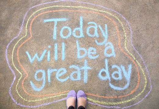 Feet standing by a chalk message that says Today will be a great day