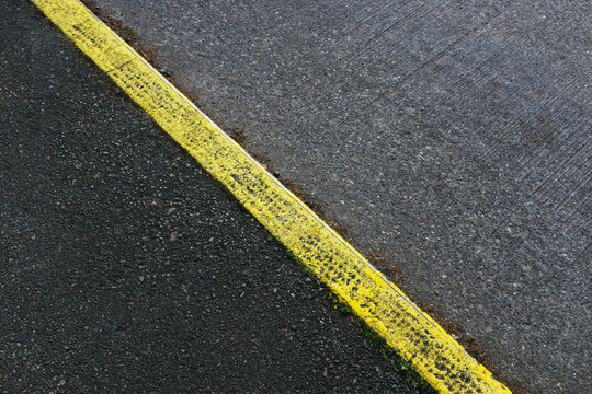 Painted yellow curb separating sidewalk and street