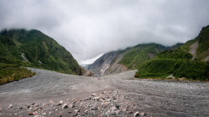 People hiking through rugged terrain in Waiho River Valley on the track to Franz Josef Glacier...