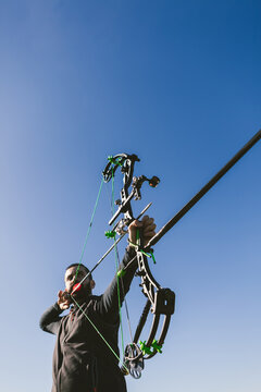 Male Archer with Professional Compound Bow against Blue Sky
