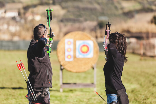 Two Archers Male and Female Aim at Target Outdoors