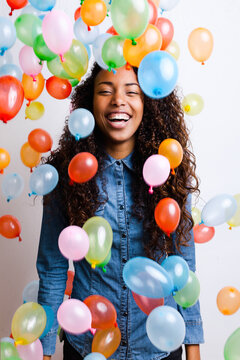 Young african woman playing with many colorful balloons.