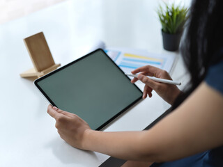 Cropped shot of female designer working with blank screen tablet in modern workspace
