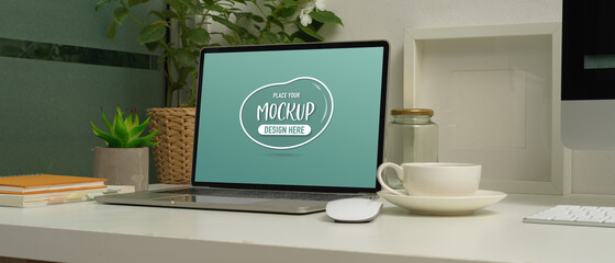 Close-up view of mock up laptop on working table with coffee cup and decorations