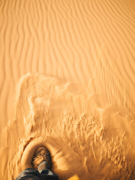 Step in the desert with sand flying away from the shoe