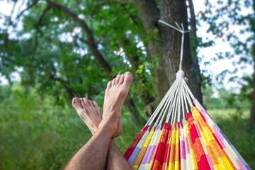 human rest in a hammock in a forest, human legs on a hammock background