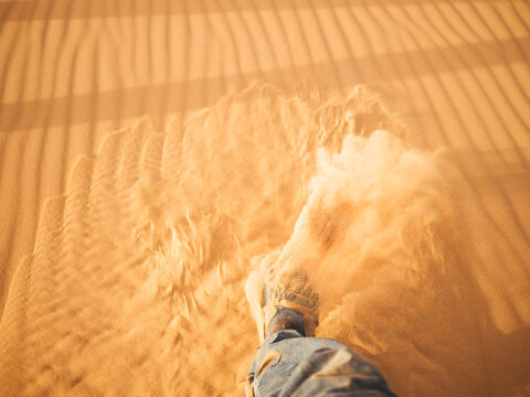Step in the desert with sand flying away from the shoe