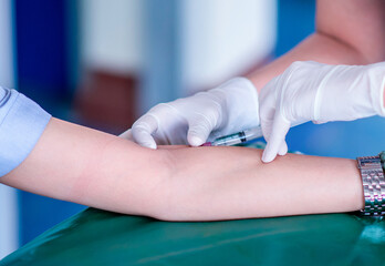 nurse/doctor trying to injecting herself with a syringe into a blood vessel on The patient arm....