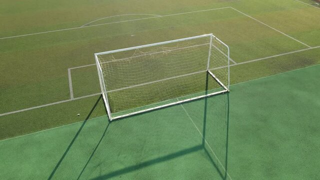 Aerial view drone flying around an empty soccer goal, football field during sunset in the stadium. No people view in summer, sports soccer recreation concept footage. Red racing track Shanghai China.