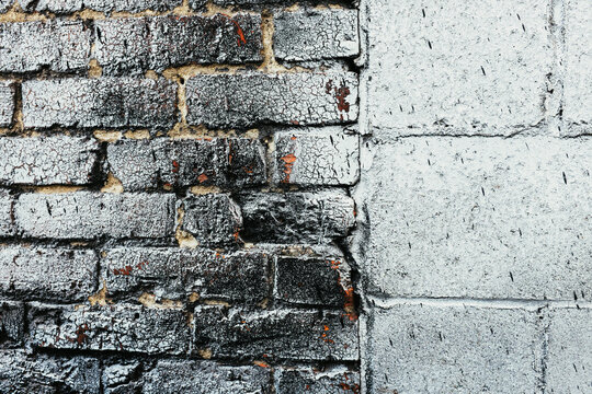 Close up eroding and cracked silver paint on brick and cinder block wall