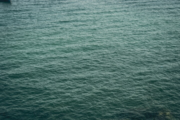 Background shot of aqua tropical sea blue water surface. Dark toned photo abstract sea ripples natural background. Ideal for design wallpaper