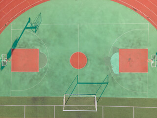 Drone aerial view of the basketball field running track and goal in stadium. Green basketball court...