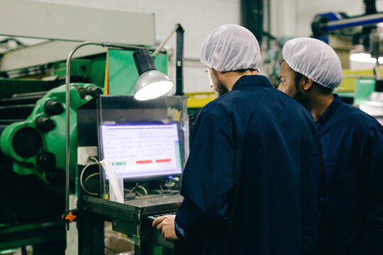 Two co-workers using a computer in a factory.
