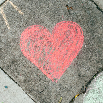 Drawing of a red heart on a sidewalk.