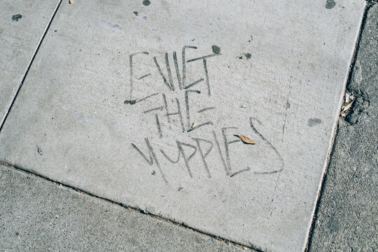 Evict the Yuppies"" drawn on a sidewalk.