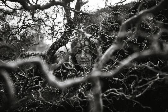 Woman seen through the curly branches of a Hazel tree.