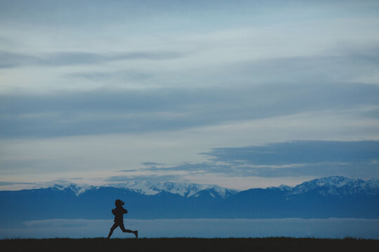 Young east indian woman running outside in early morning with mountain view