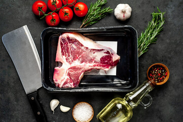 raw t-bone steak vacuum packed with
ingredients on stone background