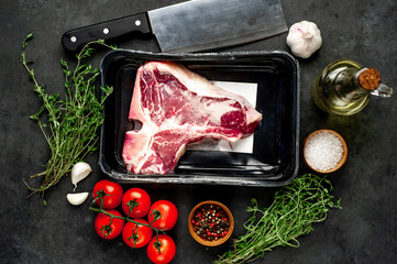raw t-bone steak vacuum packed with
ingredients on stone background