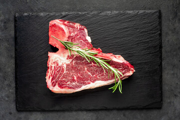 raw t-bone steak with  on stone background