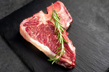 raw t-bone steak with  on stone background