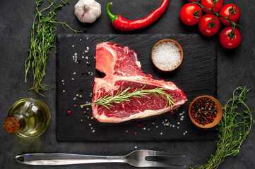 raw t-bone steak with ingredients  on stone background
