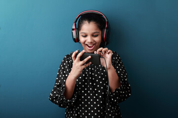 Excited young girl wearing head set engaged with a smart phone