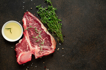 
raw t-bone steak with ingredients on stone background with copy space for your text