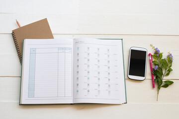 notebook account planner  and mobile phone for business work arrangement flat lay style on background white at office 