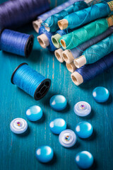 Fototapeta na wymiar Sewing threads and sewing buttons, spools in blue tone