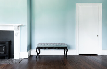 a vintage bench seat with a blue cushion, against a blue wall,