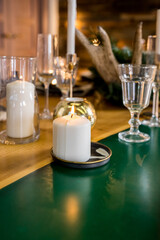 A decorated christmas dining table with wine glasses and christmas lights .Festive table setting among winter decorations and white candles. family dinner.New year candle ornament on wooden table