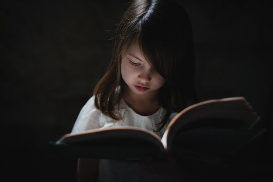 Preschool girl looking down at book