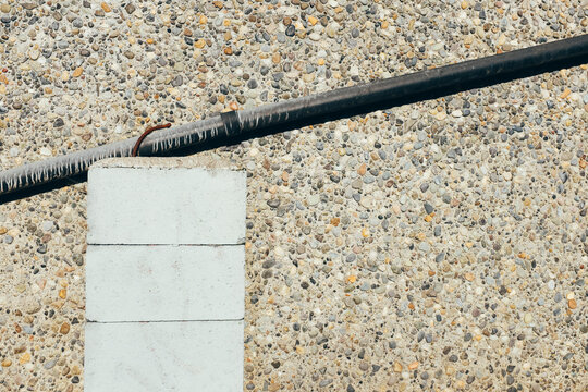 Stucco wall with gutter piping supported by cinder blocks