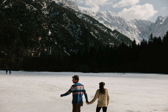 Couple in love holding hands while walking on frozen lake
