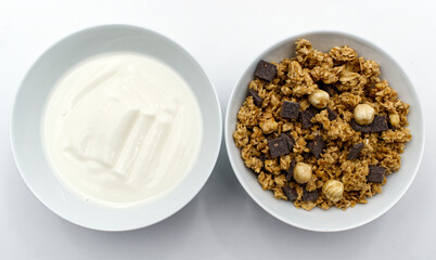 Bowl of mixed Muesli and a cup of white yogurt isolated on white background